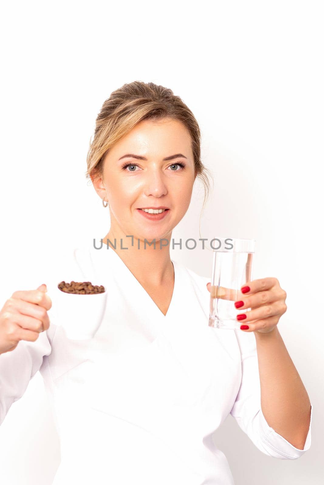 Coffee with water. The female nutritionist holds a cup of coffee beans and a glass of water in her hands on white background