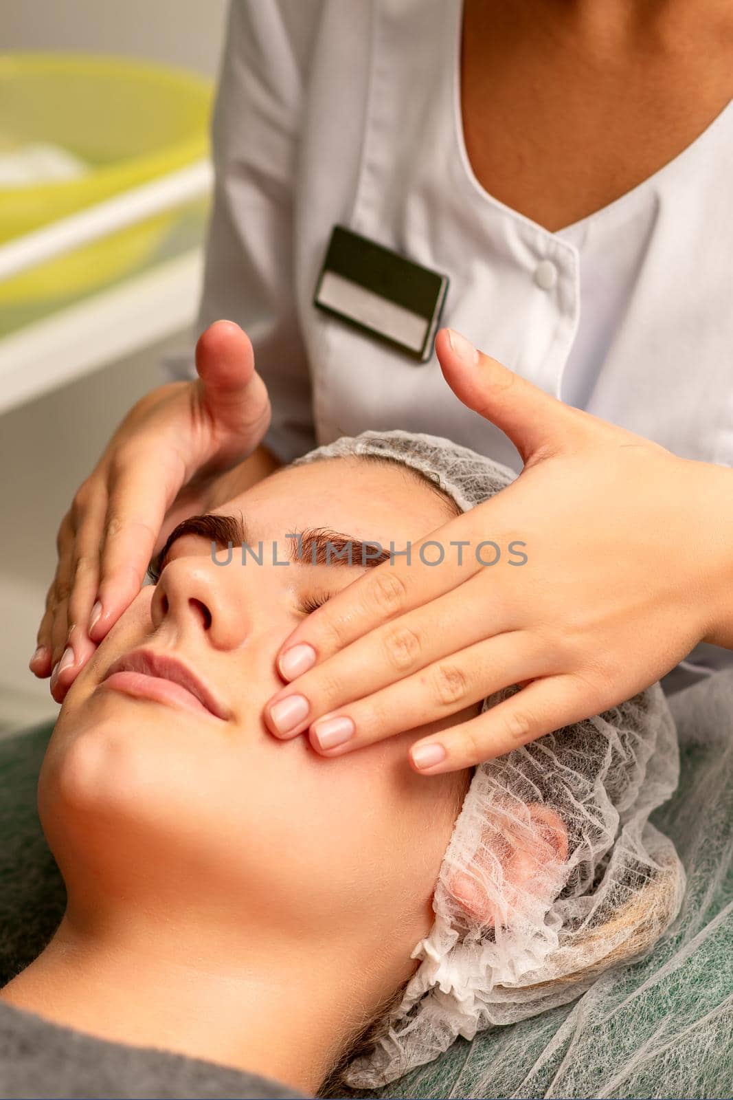 Face massage. Beautiful caucasian young white woman having a facial massage with closed eyes in a spa salon. by okskukuruza