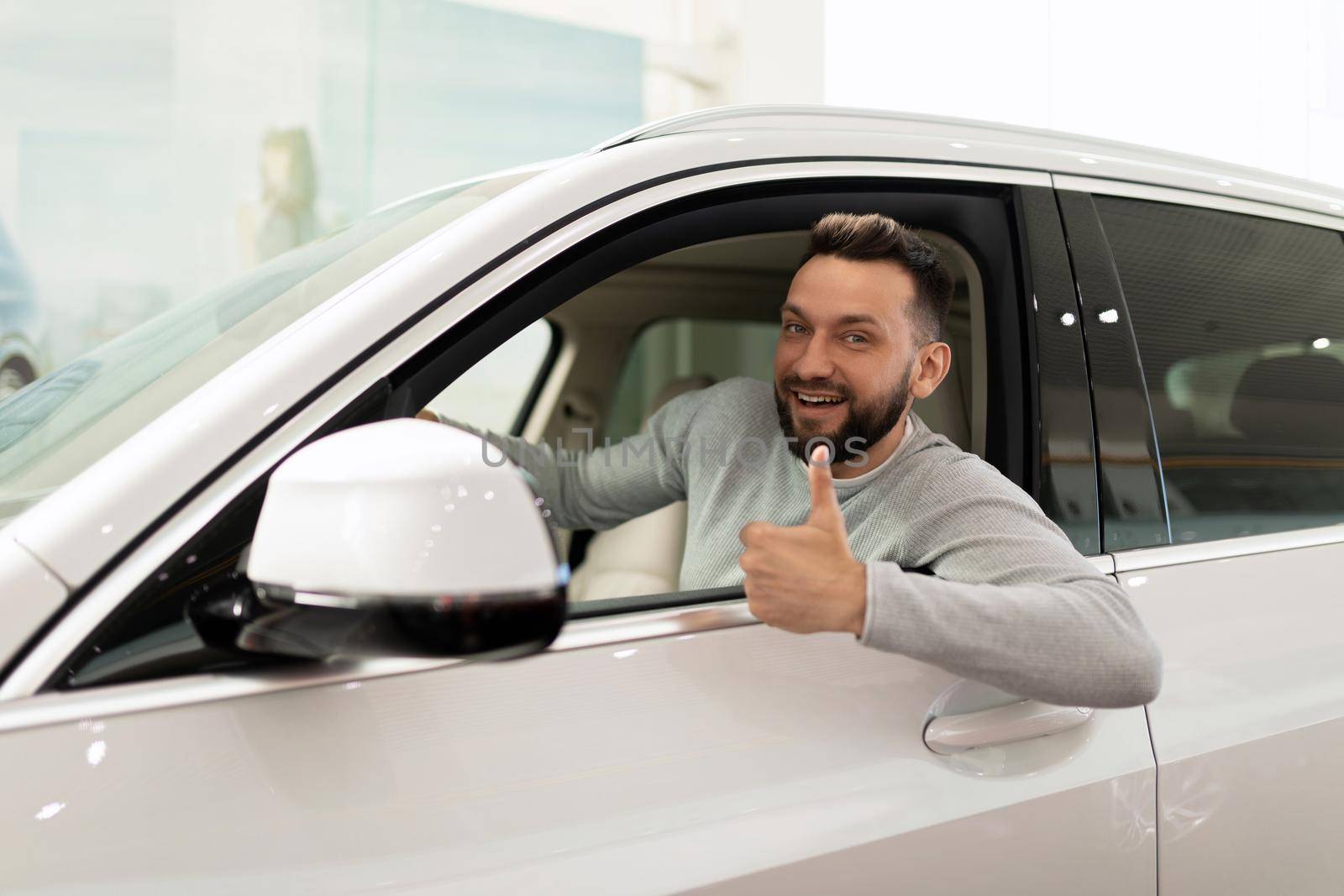 satisfied man in a new SUV bought at a car dealership with a smile on his face.