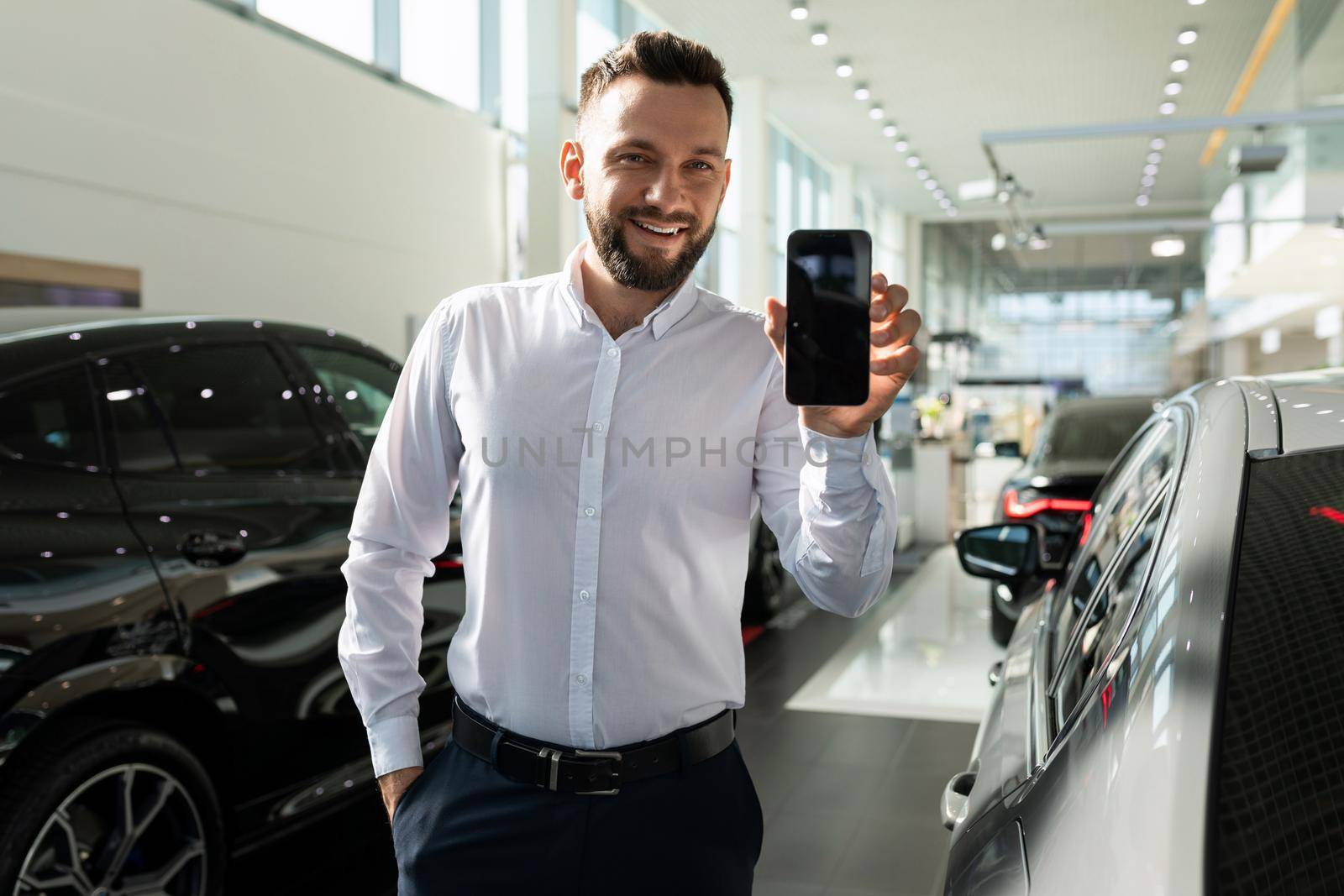 the owner of a new car in a car dealership does not show the smartphone screen.