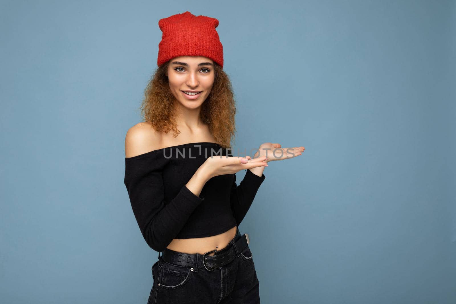 Portrait of beautiful fascinating emotional positive joyful happpy female promoter pointing to the side at copy space for advertising wearing hipster outfit isolated over background wall with empty space with sincere emotions.