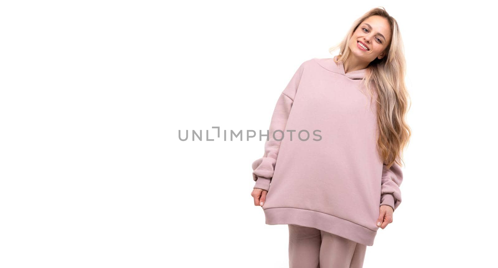 blonde with a smile on her face on a white background in a pink hoodie.