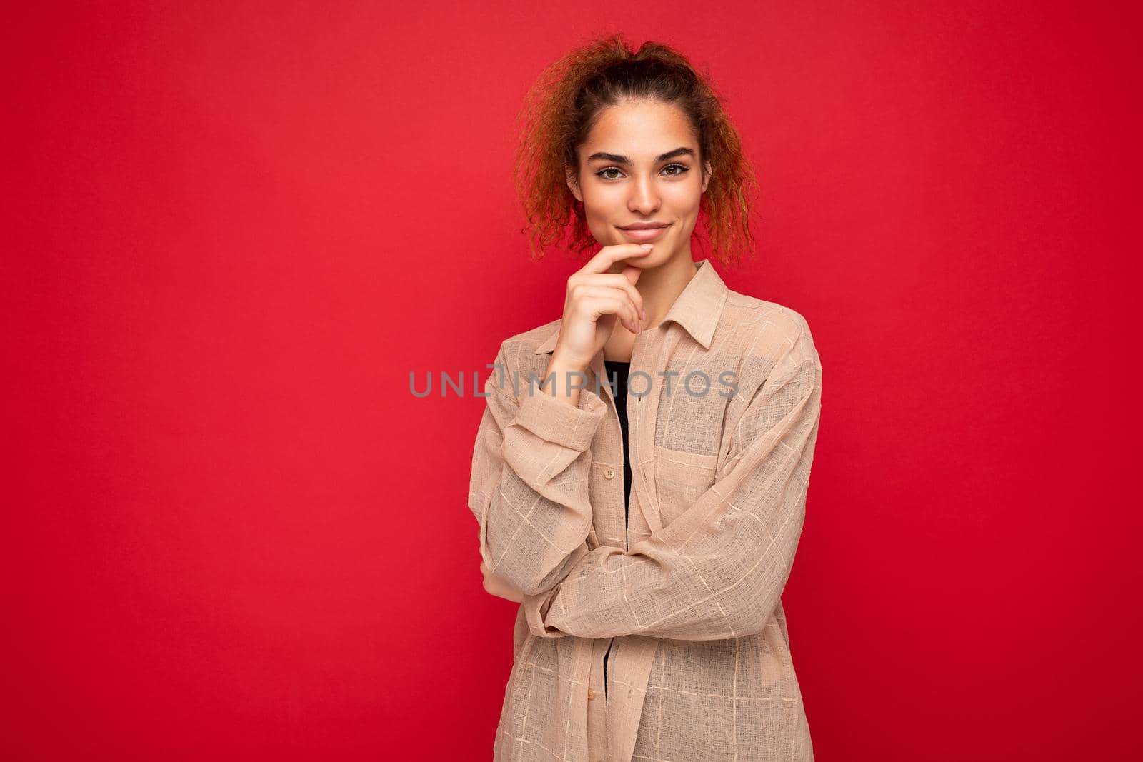 Shot of young beautiful self-confident curly woman poising isolated on background wall with copy space wearing casual beige shirt. Positive concept.