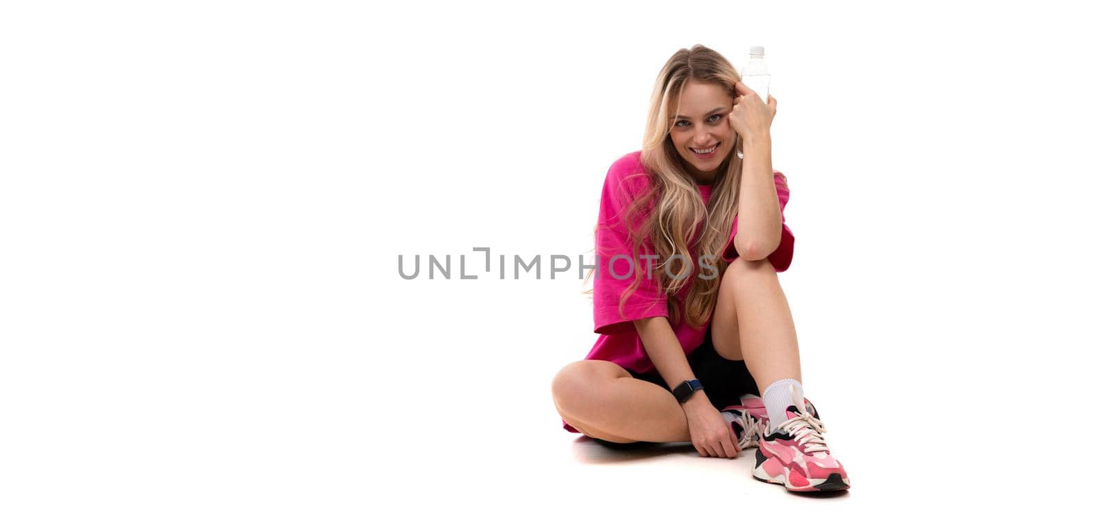 young woman in sportswear sits on the background with a smile looks at the camera.