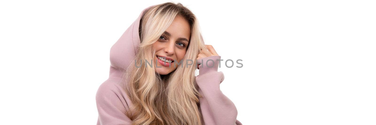widescreen photo of a blonde with a smile on her face in a pink tracksuit and a hood