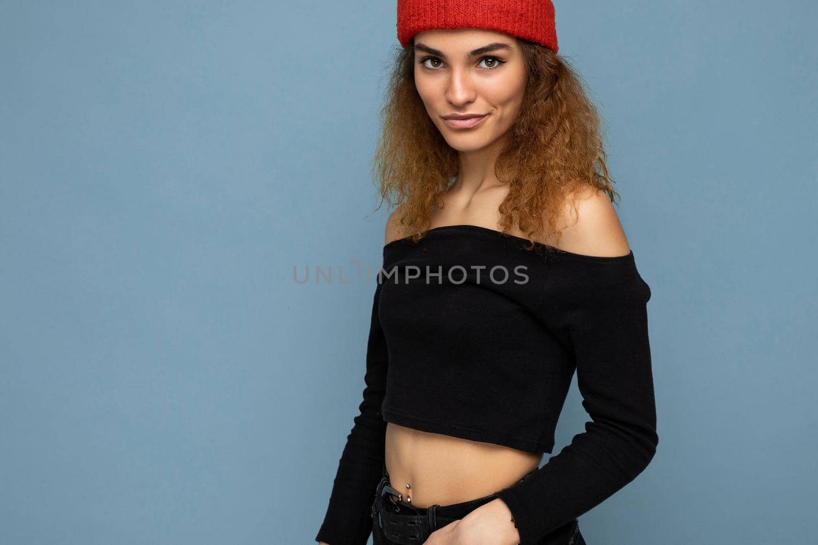 Attractive smiling happy young dark blonde woman standing isolated over colorful background wall wearing everyday stylish outfit showing facial emotions looking at camera.