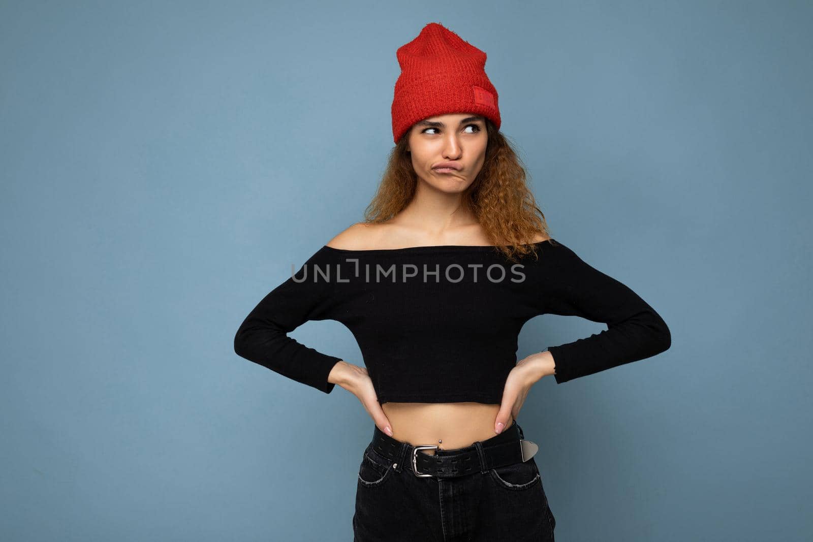 Beautiful young brunette woman isolated over blue background wall wearing casual stylish clothes feeling sincere emotions looking to the side. copy space