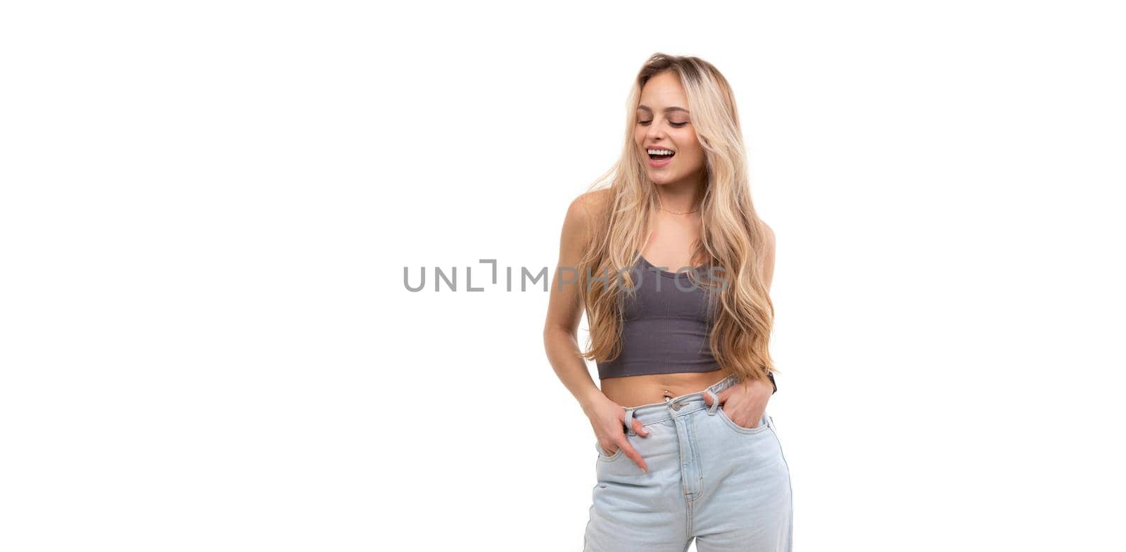 beautiful young woman in gray tank top laughing over isolated background.