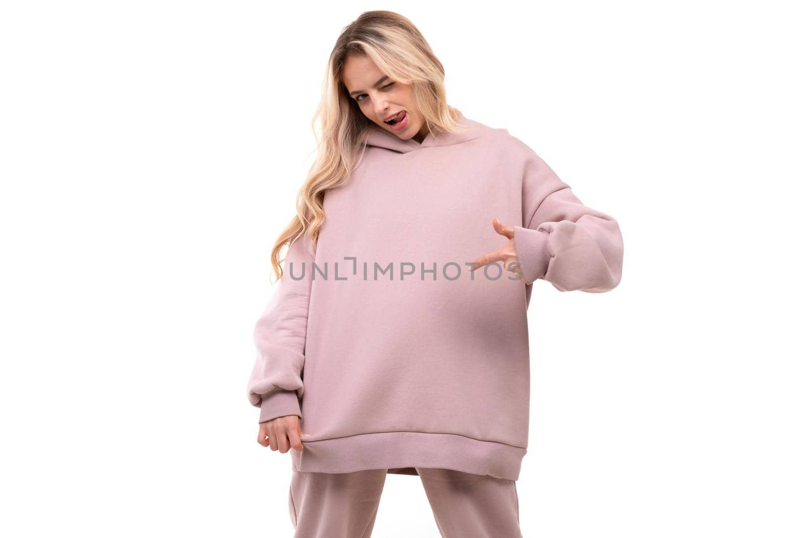 young woman in pink sports hoodie points her finger at the sweatshirt.