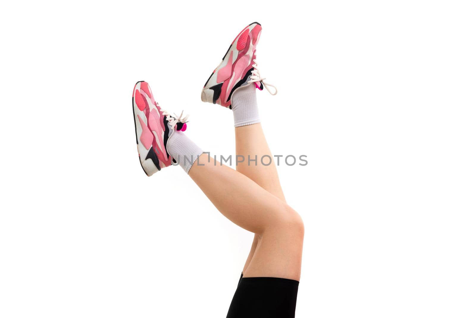 legs of a young woman in sneakers on a white background.