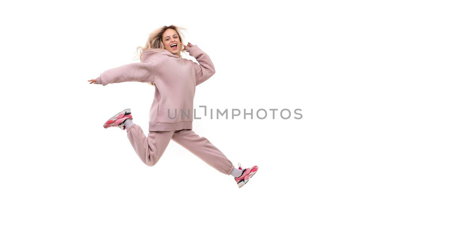 young woman in a jump in a tracksuit of beige color on a white isolated background.
