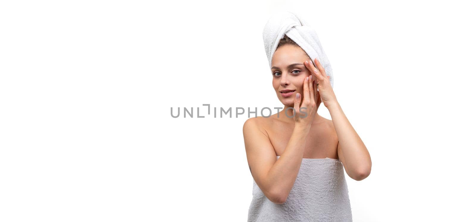 woman on white background after shower takes care of face cosmetics and skin care concept.