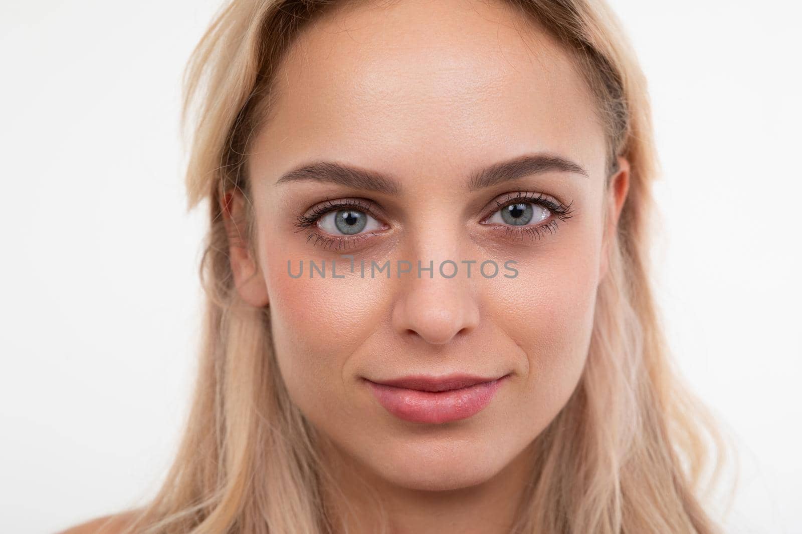 close-up portrait of a young blonde on a white background looking at the camera.