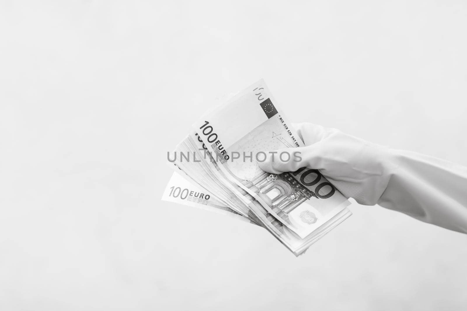 Hand with gloves receiving, giving or holding 100 EURO banknote, isolated on blurred background
