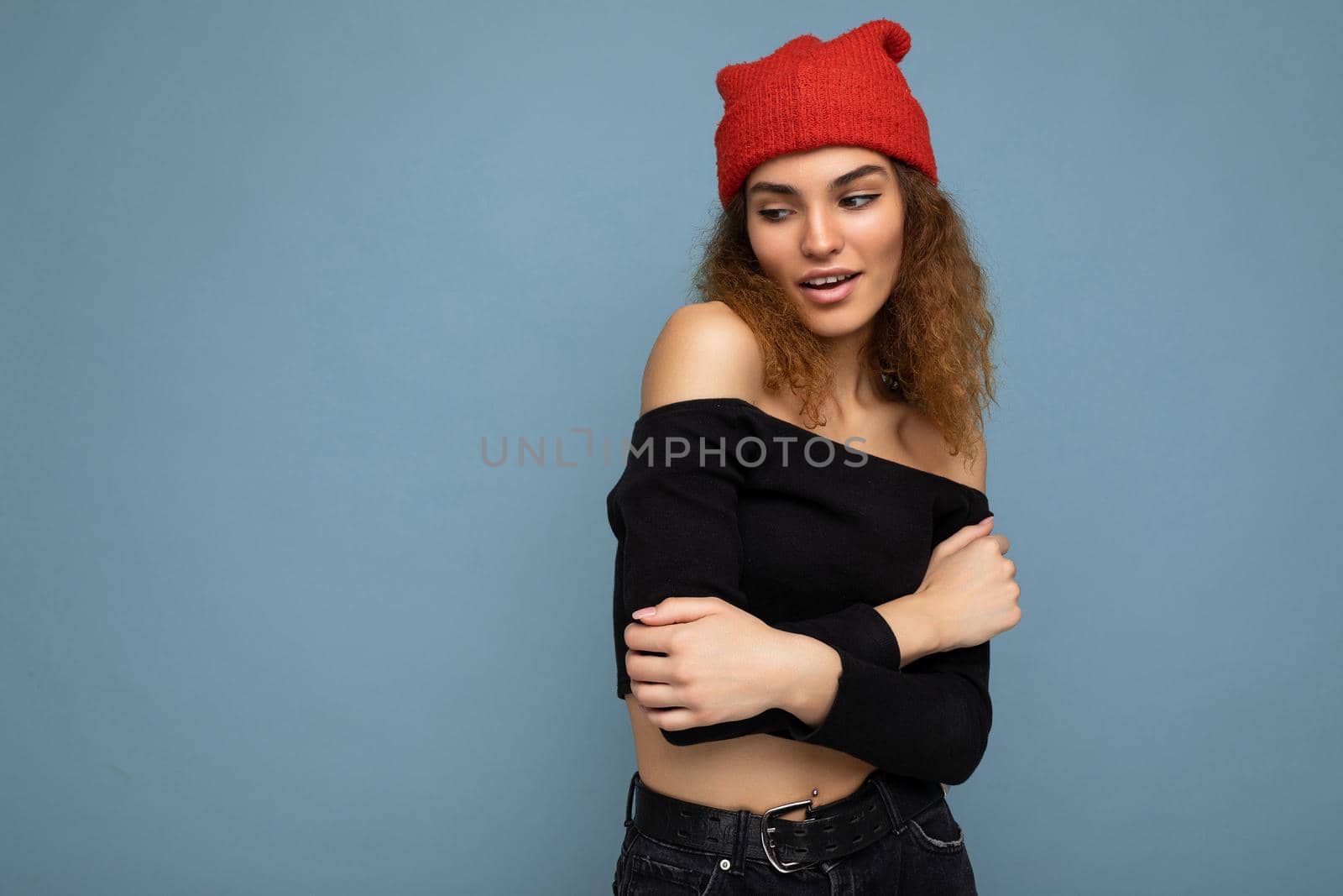 Beautiful young brunette woman isolated over blue background wall wearing casual stylish clothes feeling sincere emotions looking to the side. Copy space
