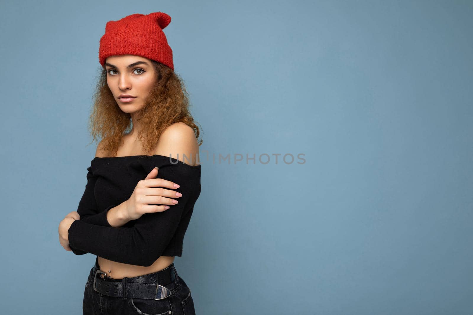 Side-profile photo of pretty serious young dark blonde woman standing isolated over colourful background wall wearing everyday trendy clothes looking at camera. Empty space
