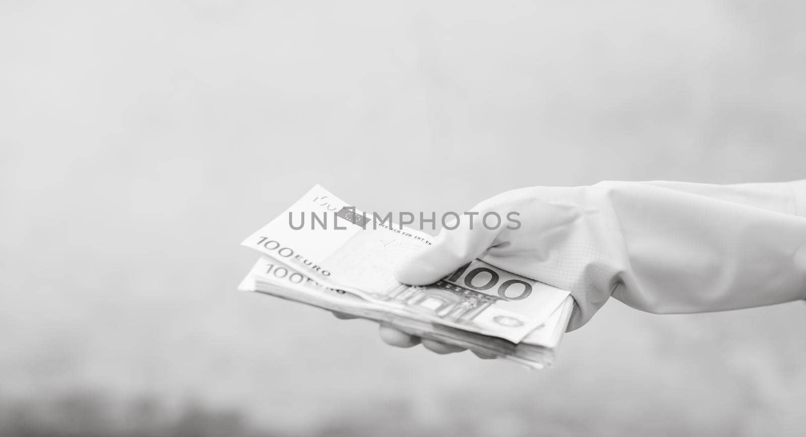 Hand with gloves receiving, giving or holding 100 EURO banknote, isolated on blurred background