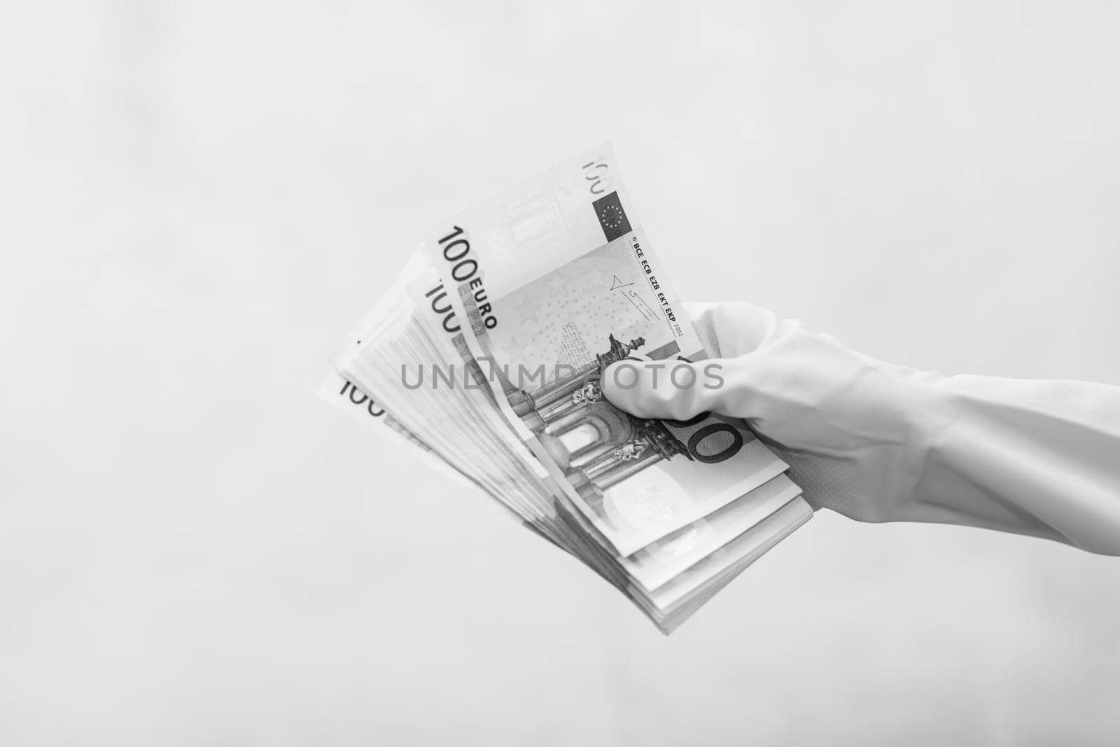 Hand with gloves receiving, giving or holding 100 EURO banknote, isolated on blurred background