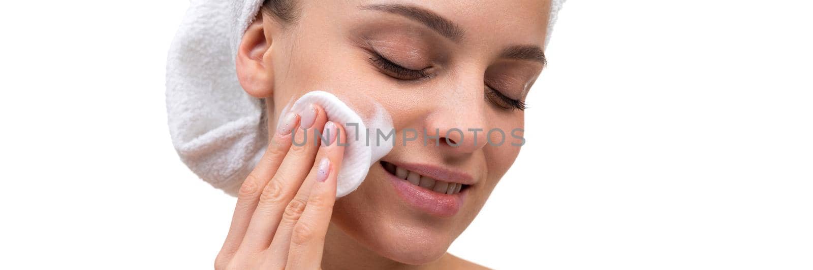 woman after shower with a cotton pad apply cream on her face skin, care at the age of 30