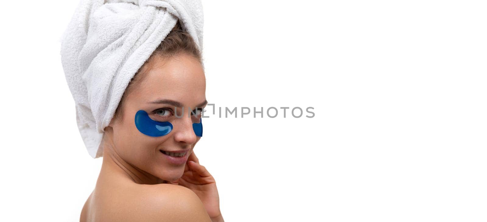 close-up portrait of middle-aged woman after shower with blue cosmetic patches on her face skin care.