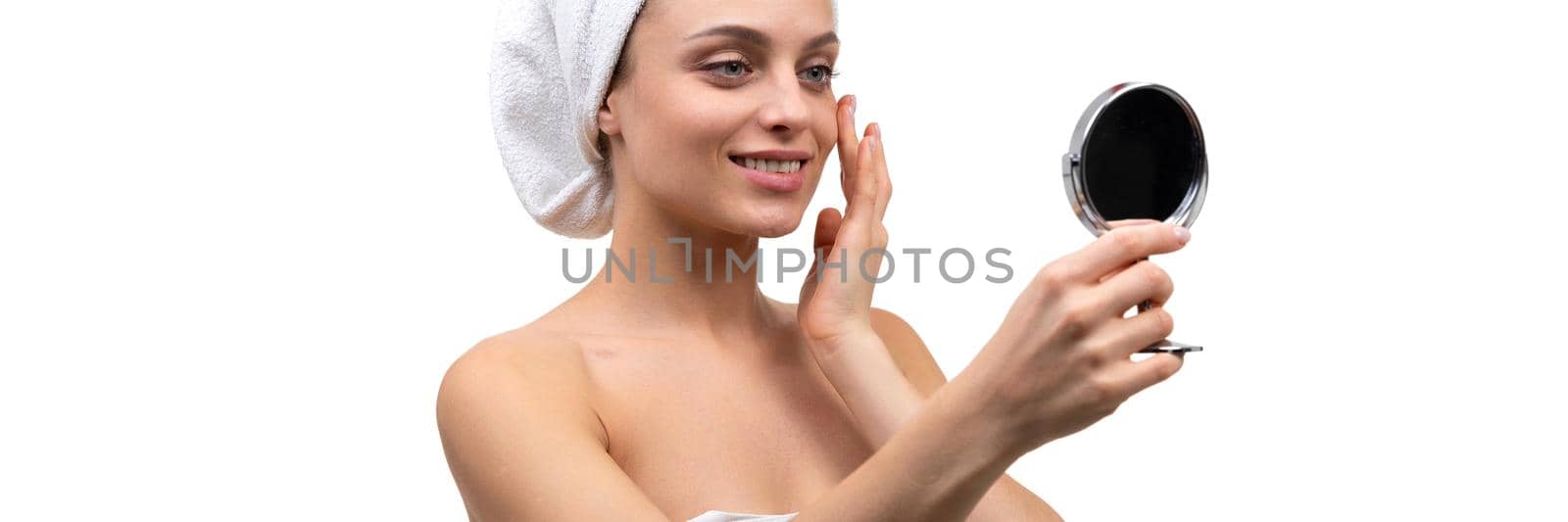 a woman after a shower admires herself in a small mirror on a white background.