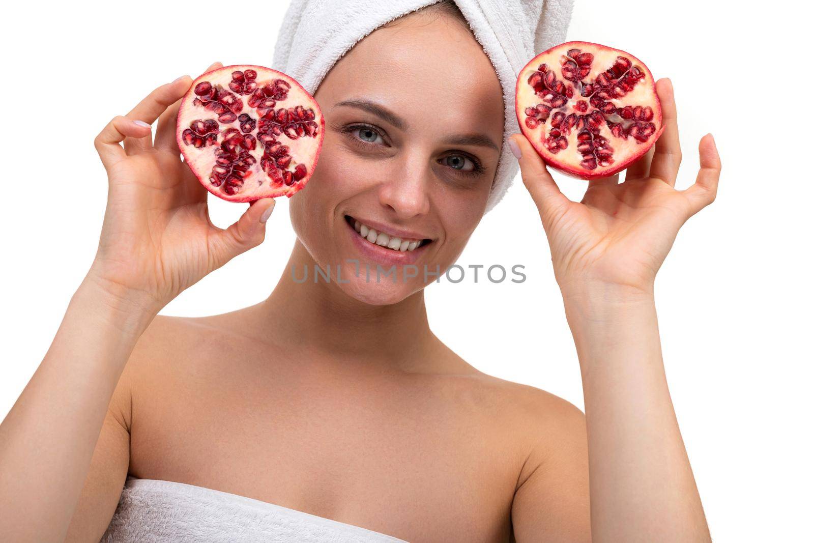beautiful middle-aged woman after cosmetic procedures holding cut pomegranate in her hands, concept of skin care and cosmetics.