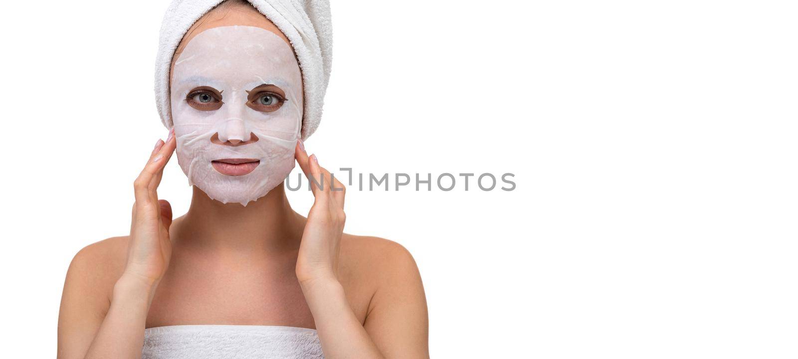 a woman after a shower with a white cosmetic mask on her face massages the skin around the cheekbones.