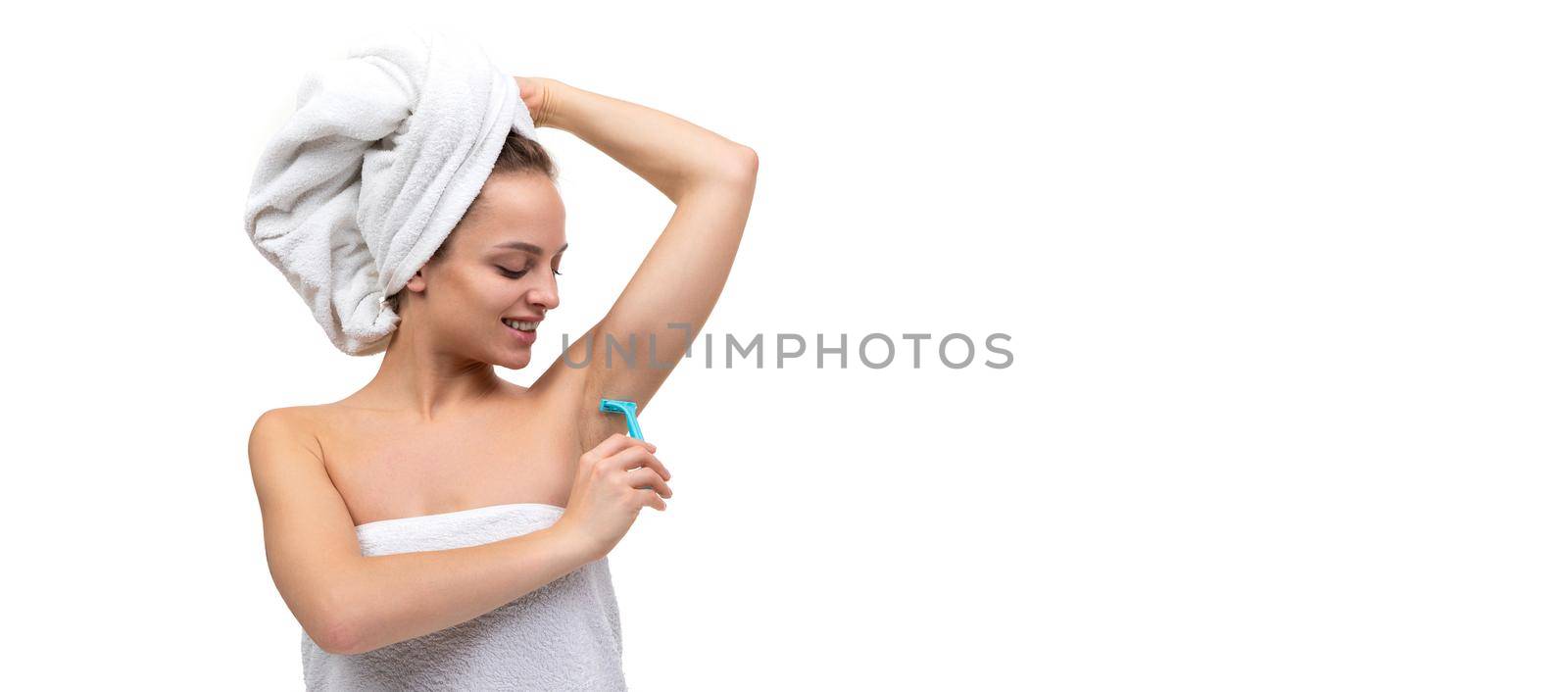 young woman with a razor removes armpit hair.