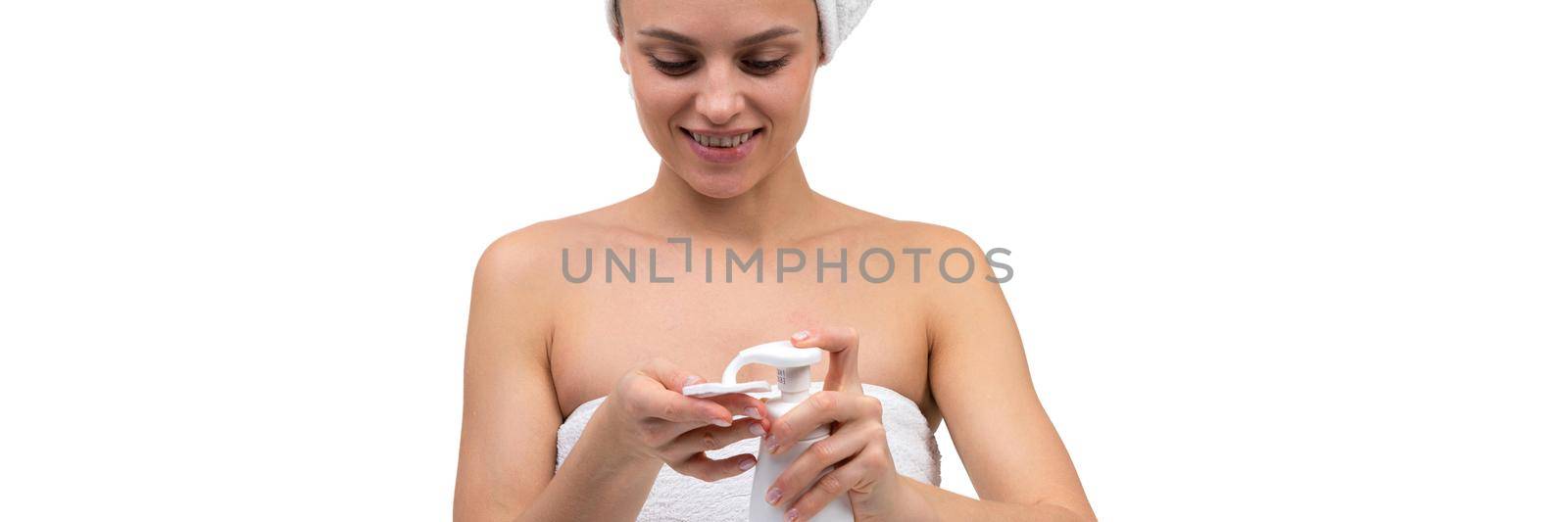 a woman after a shower applies a mousse for facial care on a cosmetic cotton pad.