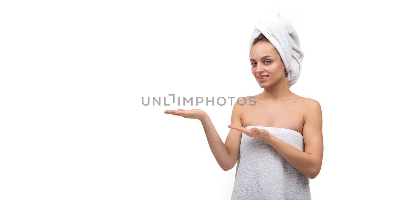 young woman in a towel on the body and head on an isolated white background holds her hand Exactly with space for the subject.