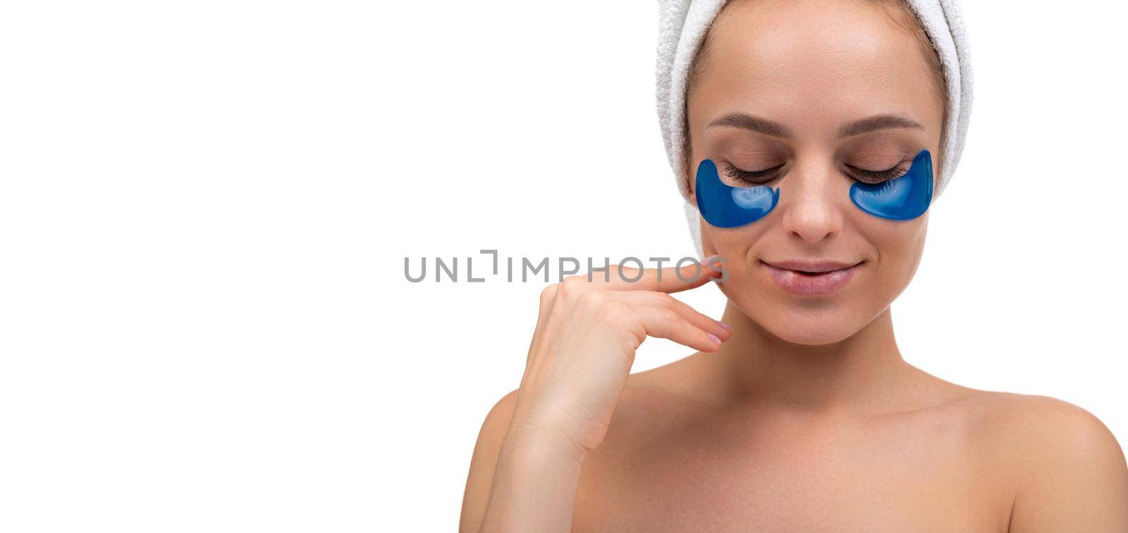 middle aged woman enjoying beauty treatments, blue cosmetic patches on her face close up.