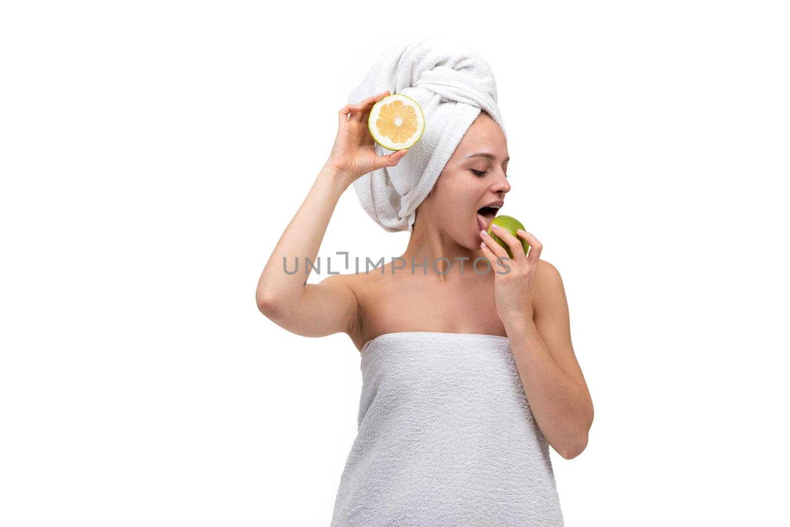 young woman after shower and cosmetic procedures dancing with fruits in her hands, cheerful mood after spa.