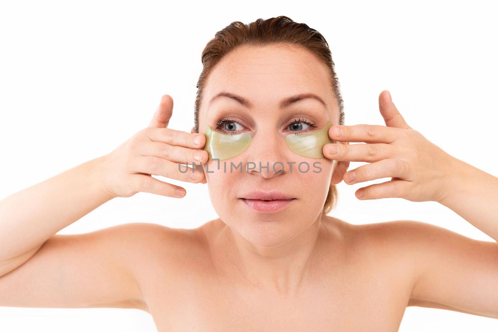 young beautiful woman after cosmetic procedures with golden cosmetic patches under eyes.