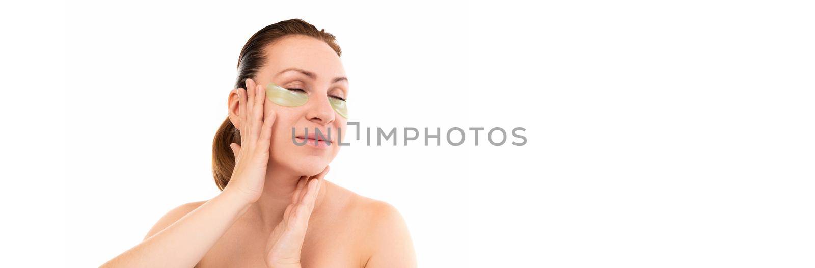 a middle-aged woman during cosmetic procedures gently touches her face.