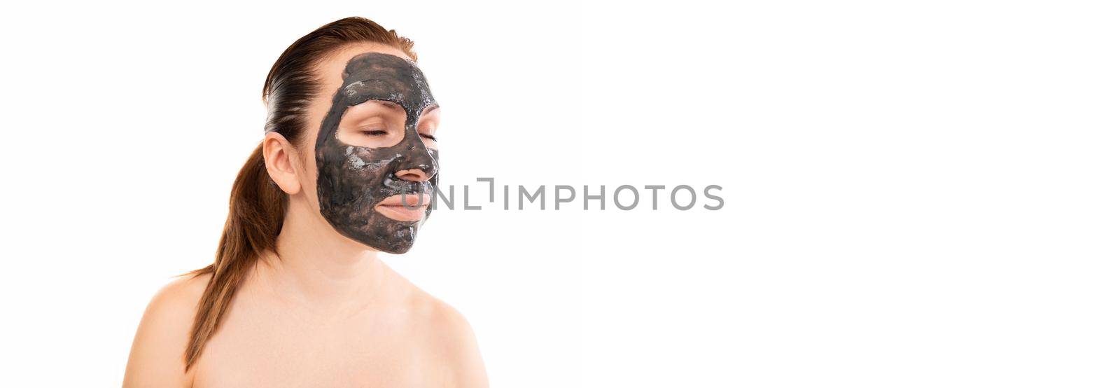 portrait of a middle-aged woman in a black cosmetic mask on her face against a white wall.