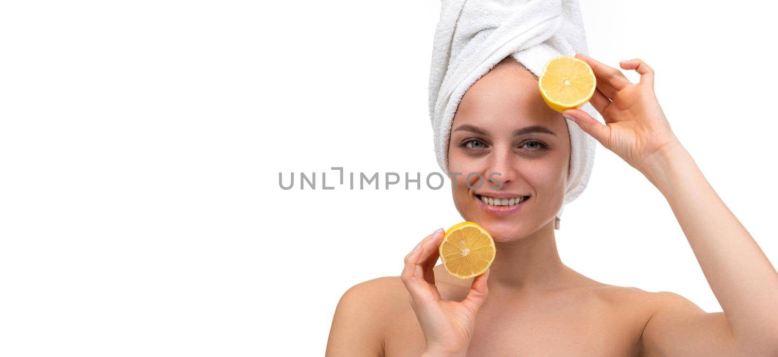 cheerful young woman with a smile on her face after a shower holds a cut orange in her hands by TRMK