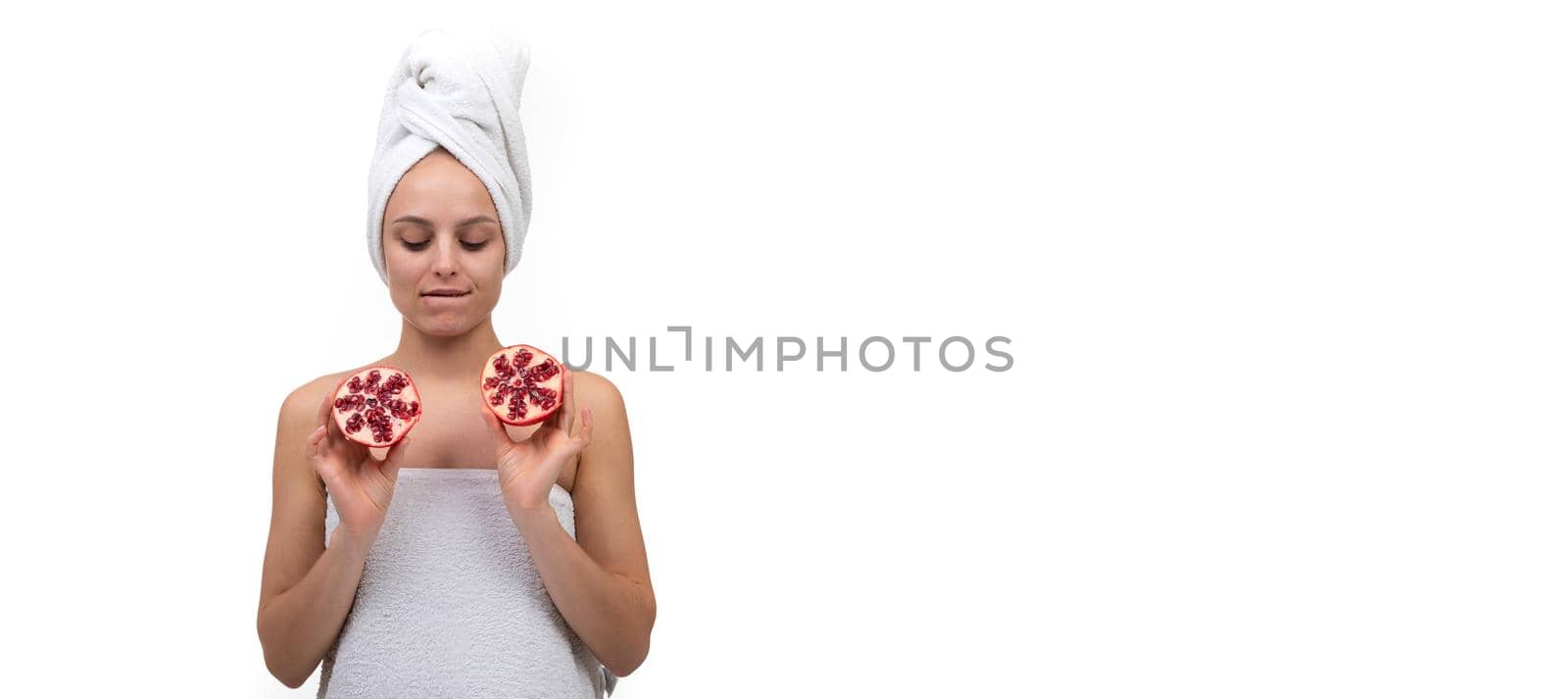 young woman after spa treatments holding cut pomegranate fruit in her hands.