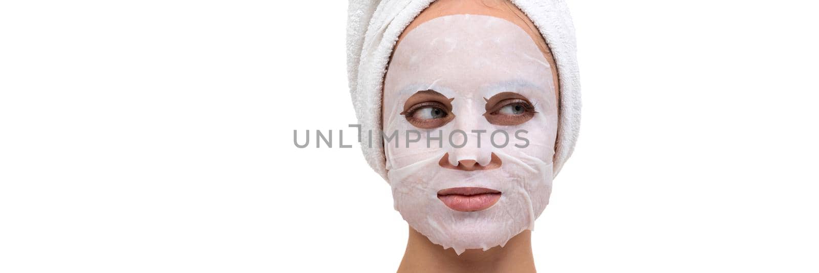 close-up portrait of a woman after a shower with a white cosmetic mask on her face made of non-woven fabric.