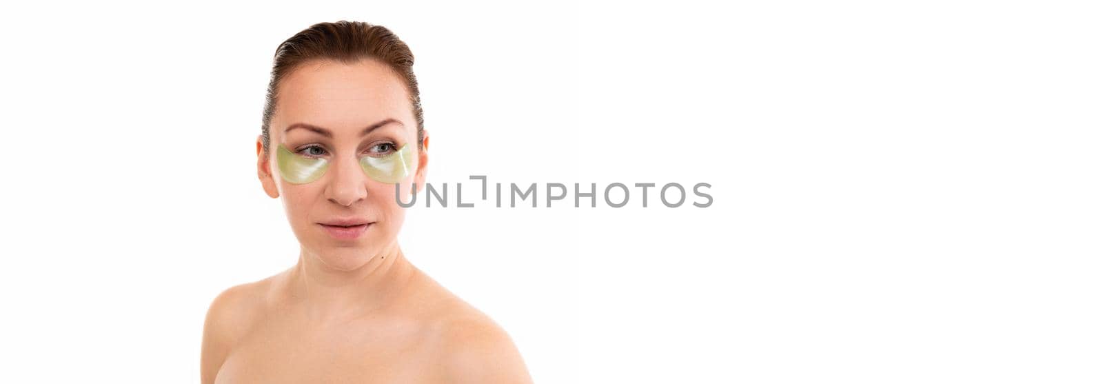 young attractive middle-aged woman with cosmetic patches under the eyes on a white background by TRMK