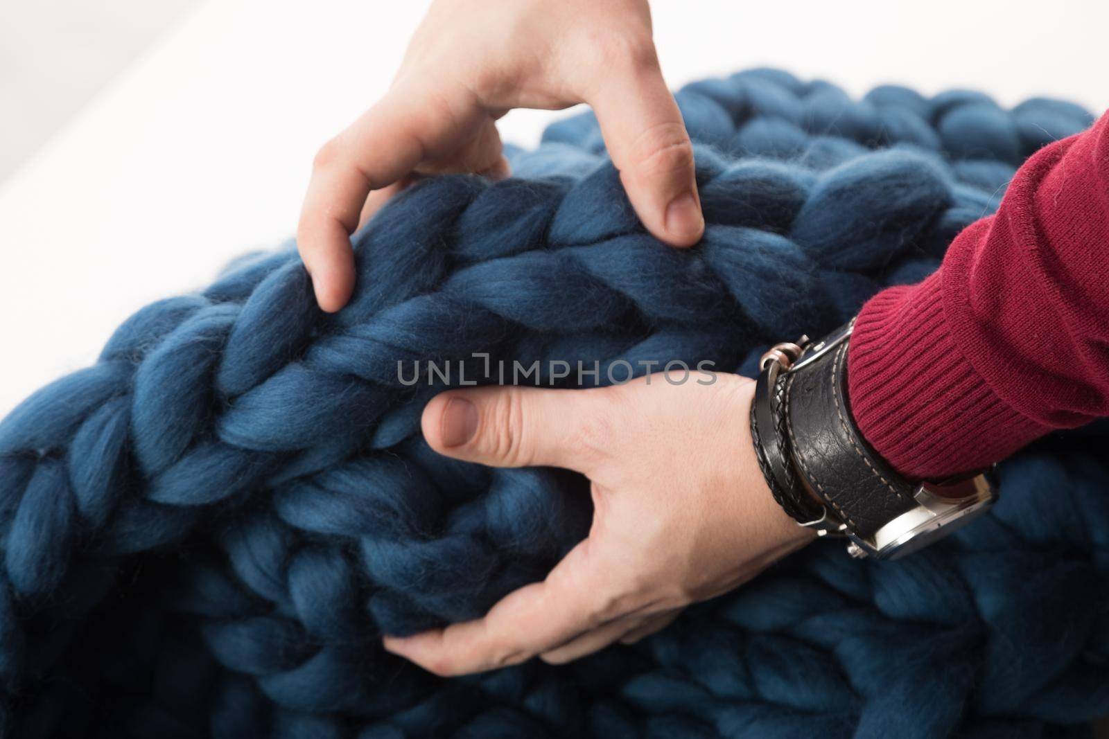 blanket made of natural sheep wool of coarse knit in men's hands.