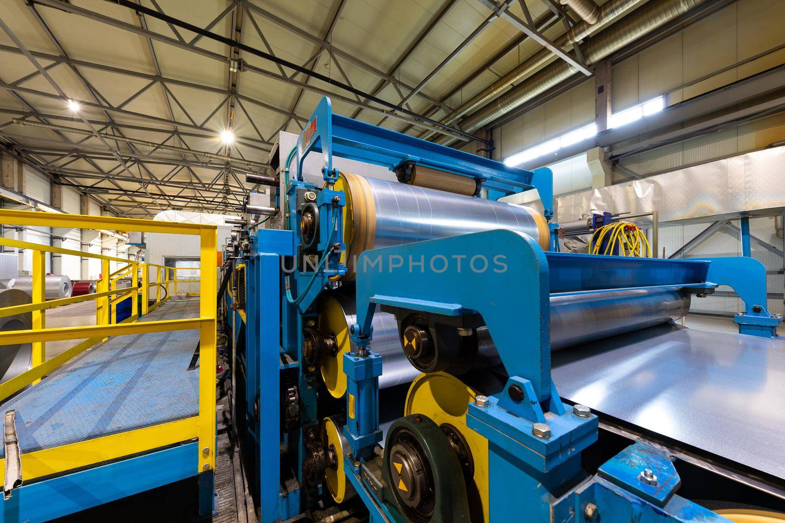Photo of steel roofing forming machine. Industrial machine for metal sheet roof coils cut. Process of making steel tile for roof.