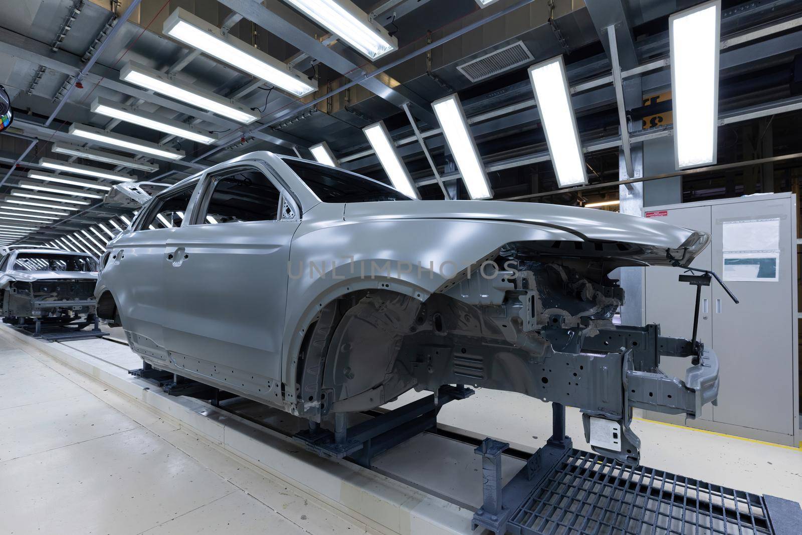 Car bodies are on assembly line. Factory for production of cars. Modern automotive industry. A car being checked before being painted in a high-tech enterprise.