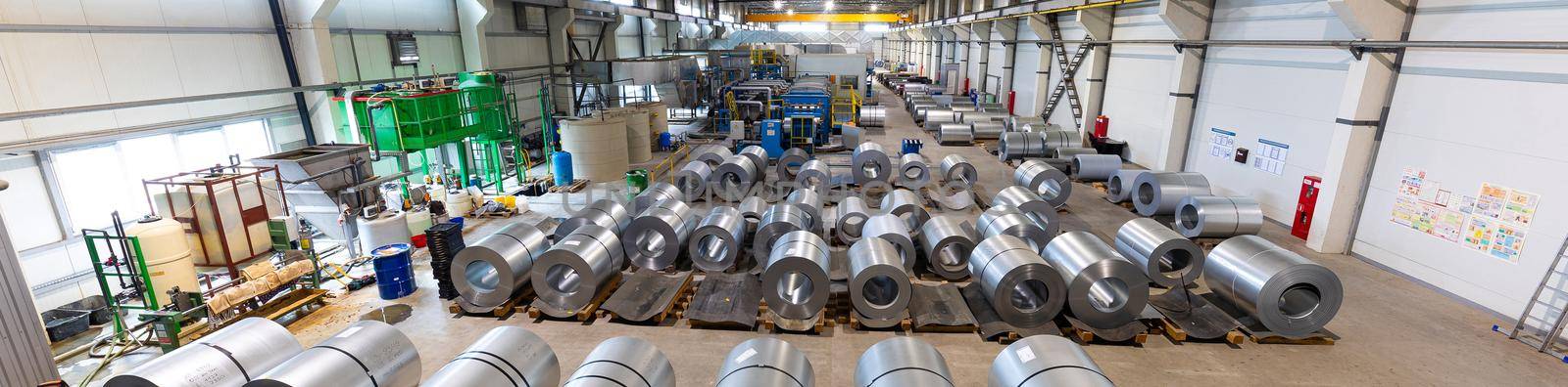 Panoramic photo of production line of metal tile for roof. Steel forming machine in metalwork factory workshop. Metal sheet profiling machine. Background of plant.
