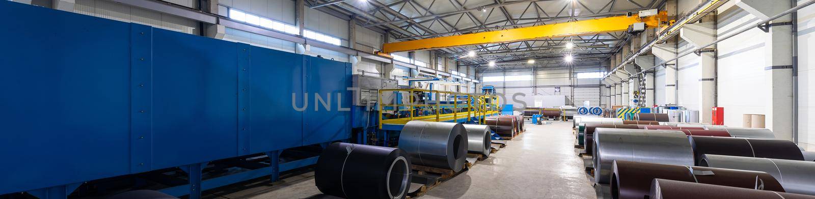 Panoramic photo of steel roofing forming machine. Industrial machine for metal sheet roof coils cut. Factory and plant background.