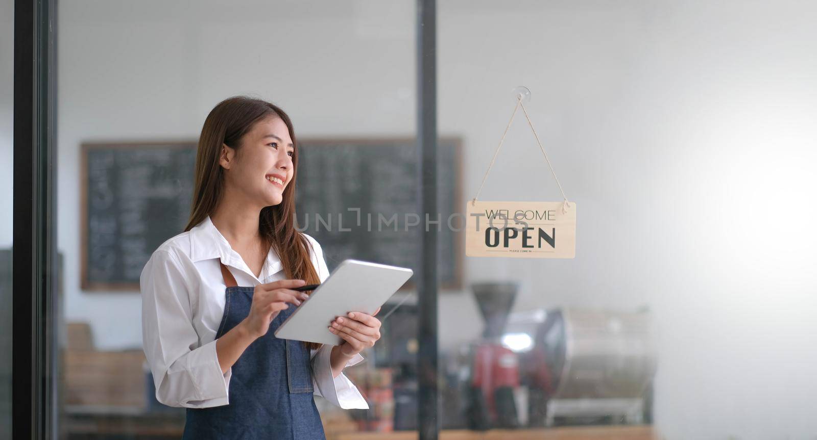 Startup successful small business owner sme beauty girl stand with tablet smartphone in coffee shop restaurant. Portrait of asian tan woman barista cafe owner. SME entrepreneur seller business concept.