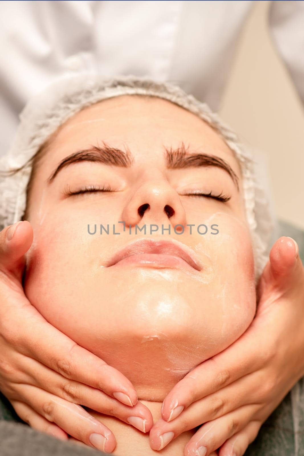 Face massage. Beautiful caucasian young white woman having a facial massage with closed eyes in a spa salon