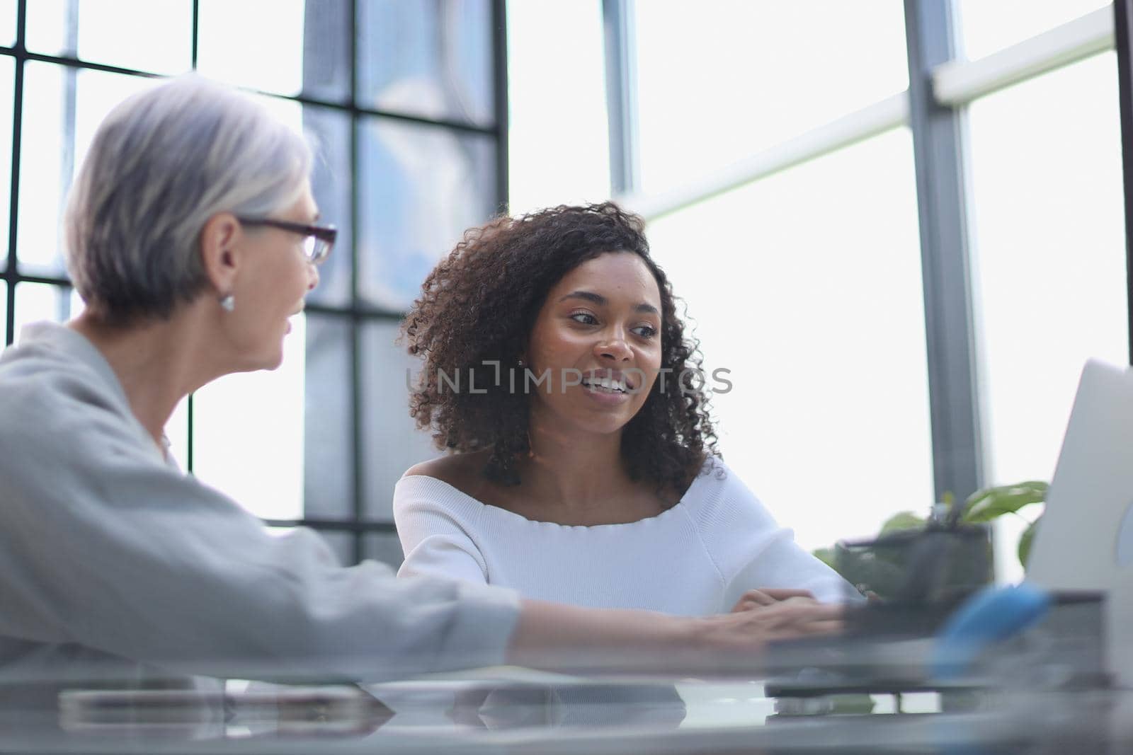 Female colleagues of different nationalities and ages met in the office hall discussing work issues