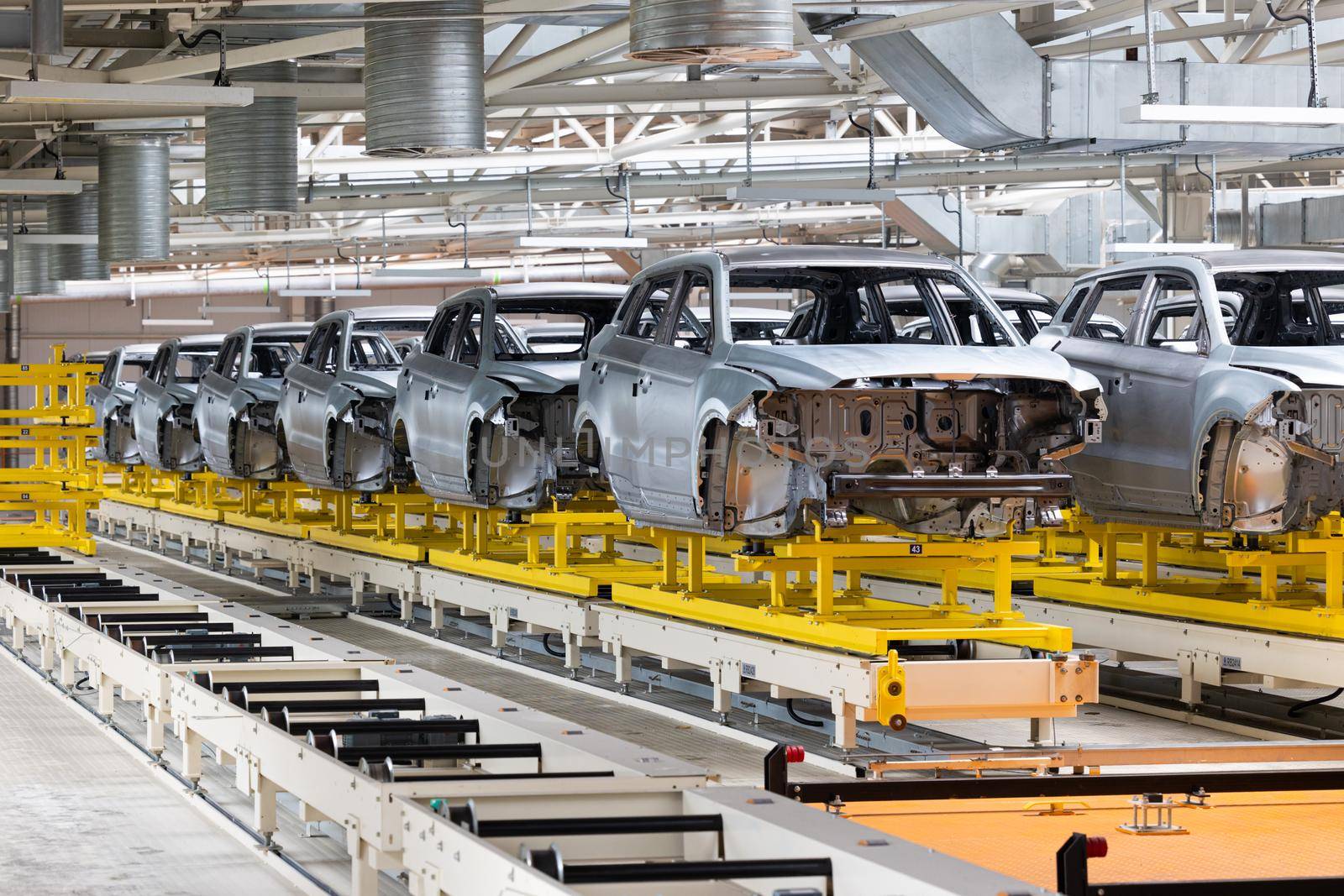 Photo of automobile production line. Modern car assembly plant. Modern and high-tech automotive industry. Conveyor of auto bodies.