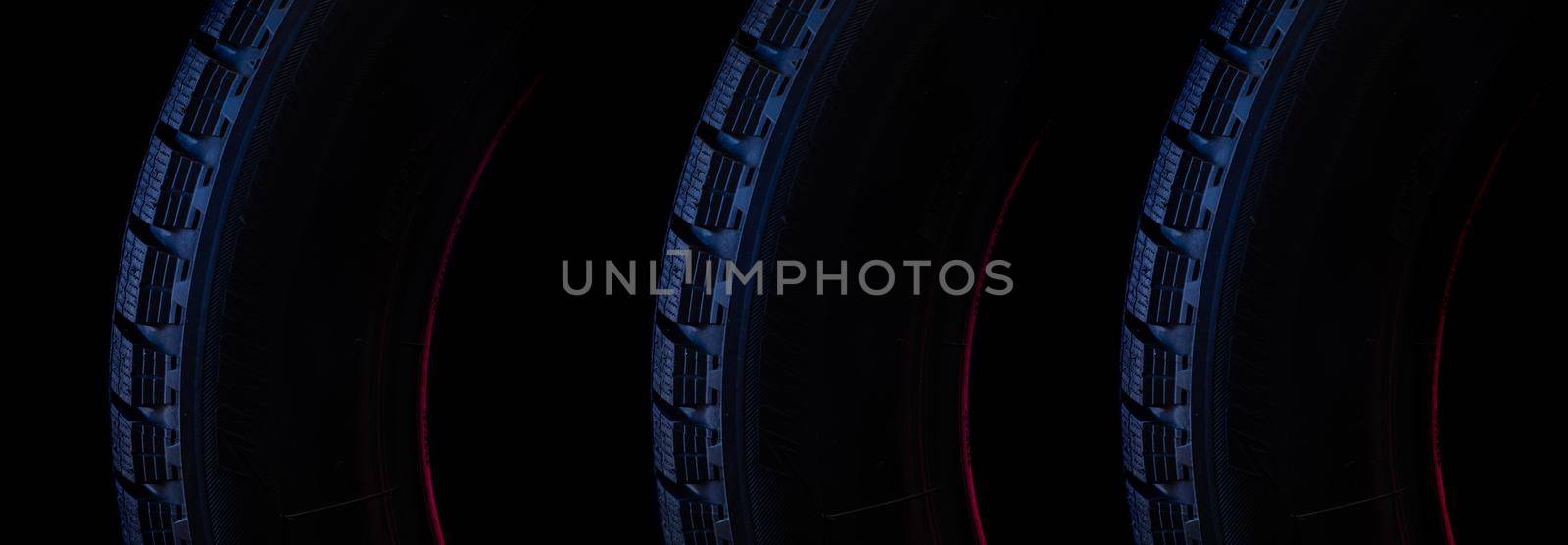 part of the tread of a winter tire on a black background close-up with blue backlight.