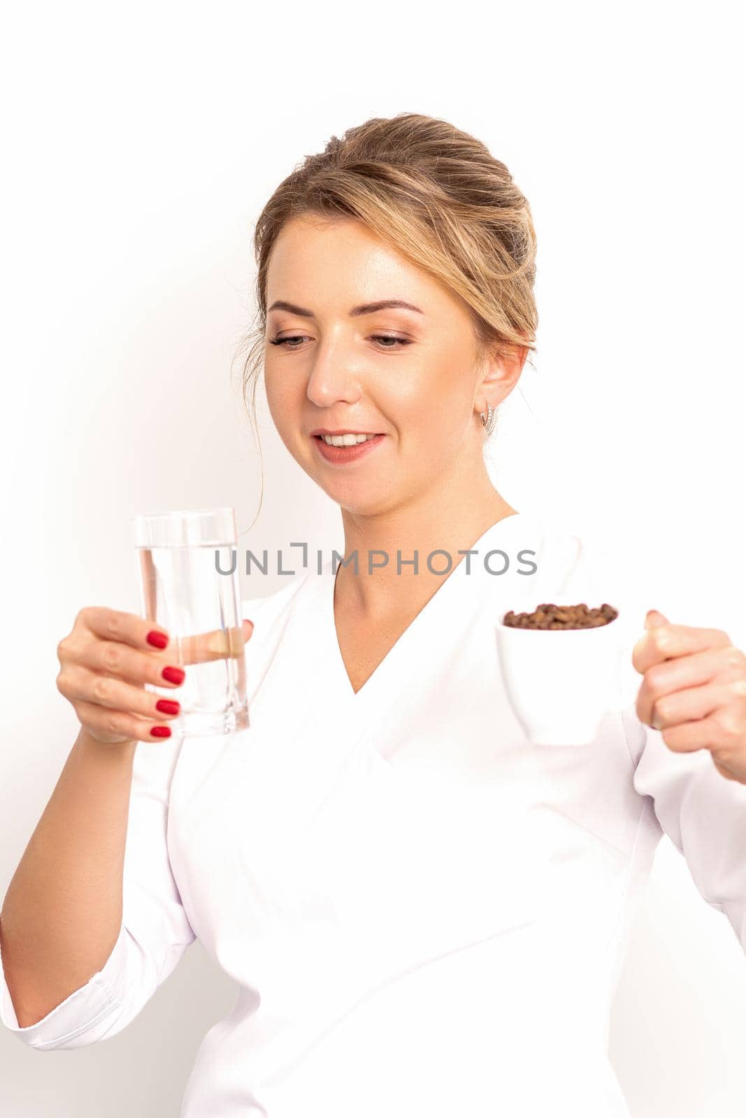 Coffee with water. The female nutritionist holds a cup of coffee beans and a glass of water in her hands on white background